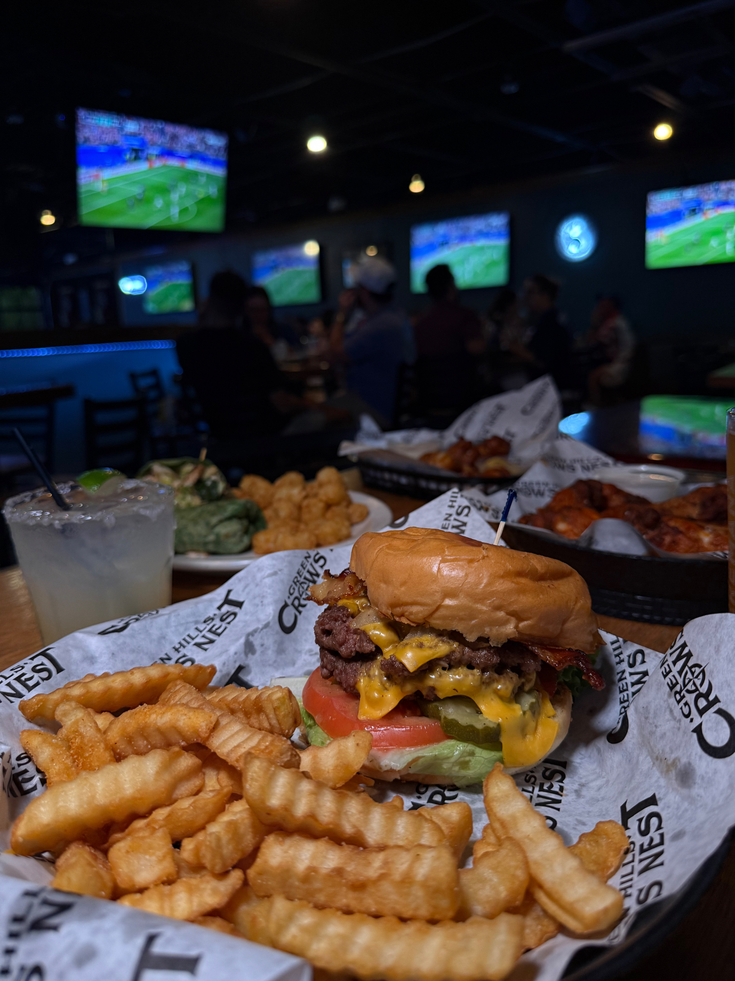 Crow's Nest burger and fries with sports playing across the bar's wall of TVs